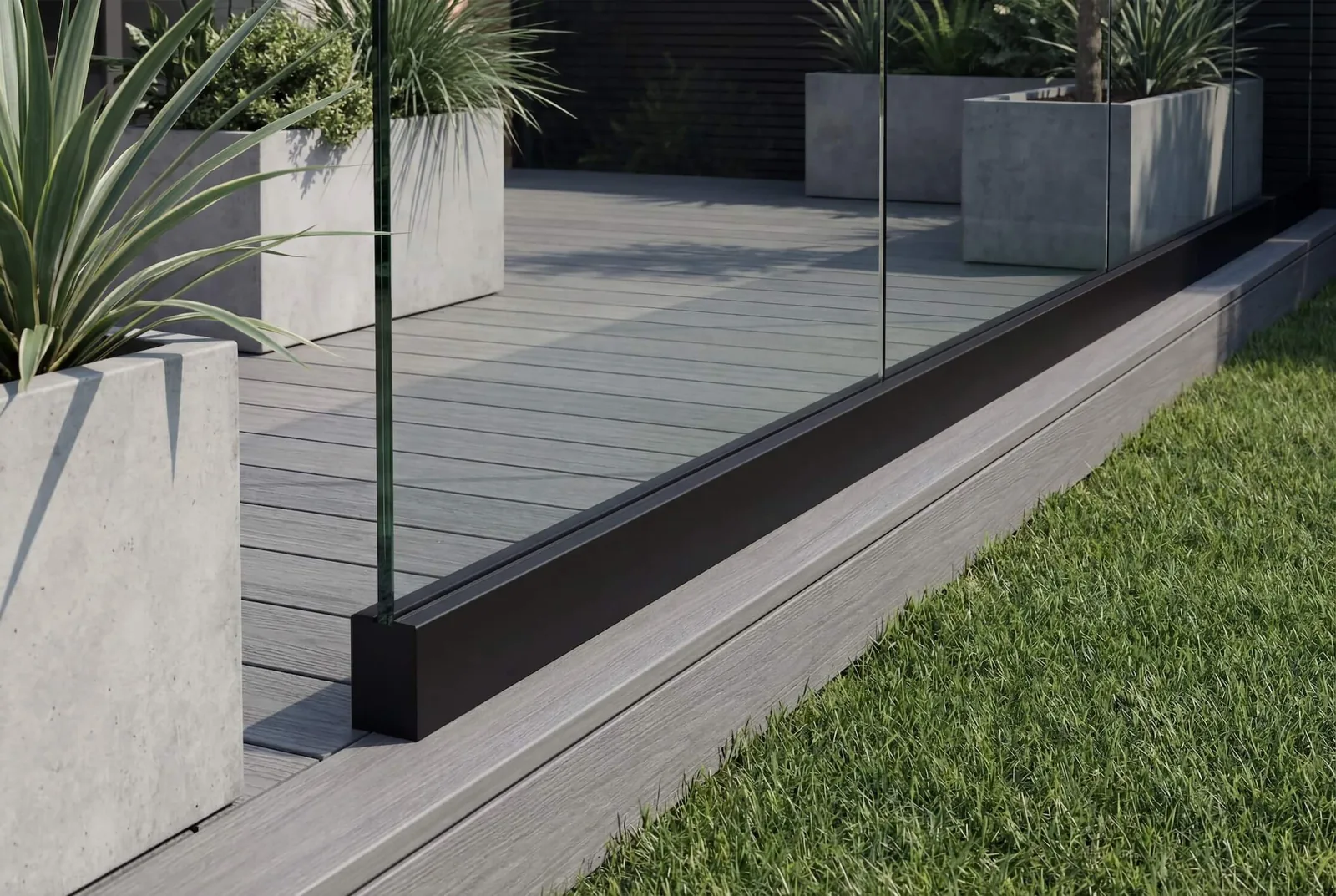 Clear frameless glass railing set in a continuous black base channel along a residential deck
