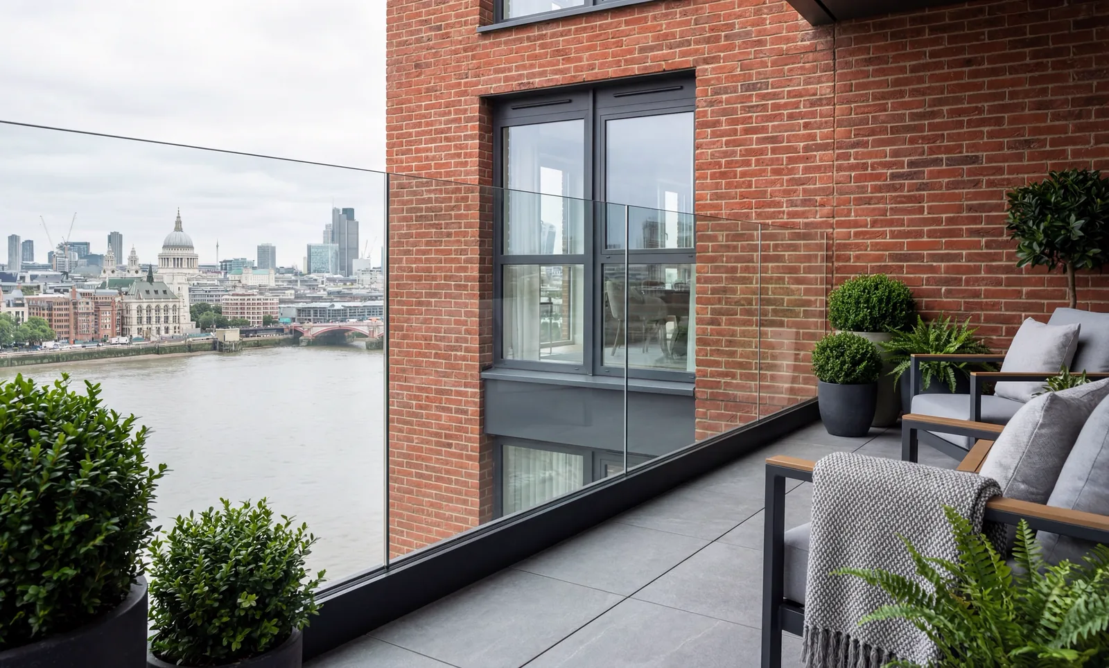 Post-free clear glass railing held in a continuous black base channel on a brick balcony